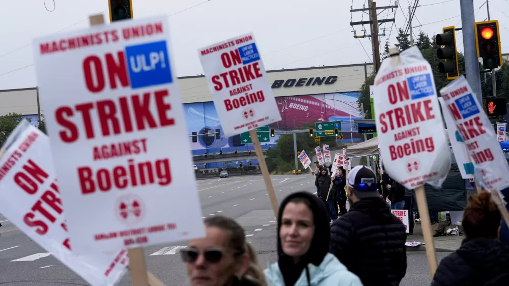 FILE - Boeing workers wave picket signs as they strike after union members voted to reject a contract offer near the company's factory in Everett, Washington, Sept. 15, 2024. (AP Photo/Lindsey Wasson)