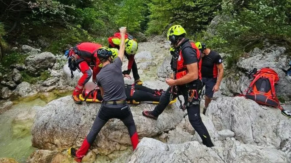 Gorski re&scaron;evalci iz Bovca pomagajo ponesrečenki pri raftingu. 