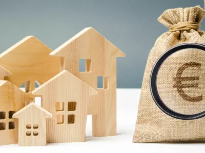 Bag with money and euro sign and wooden houses. Financing in the country. Investing money in real estate. Saving and accumulation of money. Mortgage. Buying a home. Property sale. City budget.