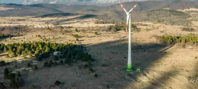 Wind turbine among ship pasture at winter sunset on Karst plateau. Behind is a mountain Nanos and village Dolenja vas.