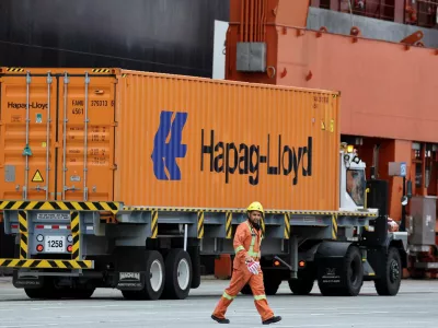 A worker walks near a truck carrying a container at the Centerm container ship terminal at the Port of Vancouver in Vancouver, British Columbia, Canada August 3, 2025. REUTERS/Chris Helgren