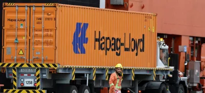 A worker walks near a truck carrying a container at the Centerm container ship terminal at the Port of Vancouver in Vancouver, British Columbia, Canada August 3, 2025. REUTERS/Chris Helgren