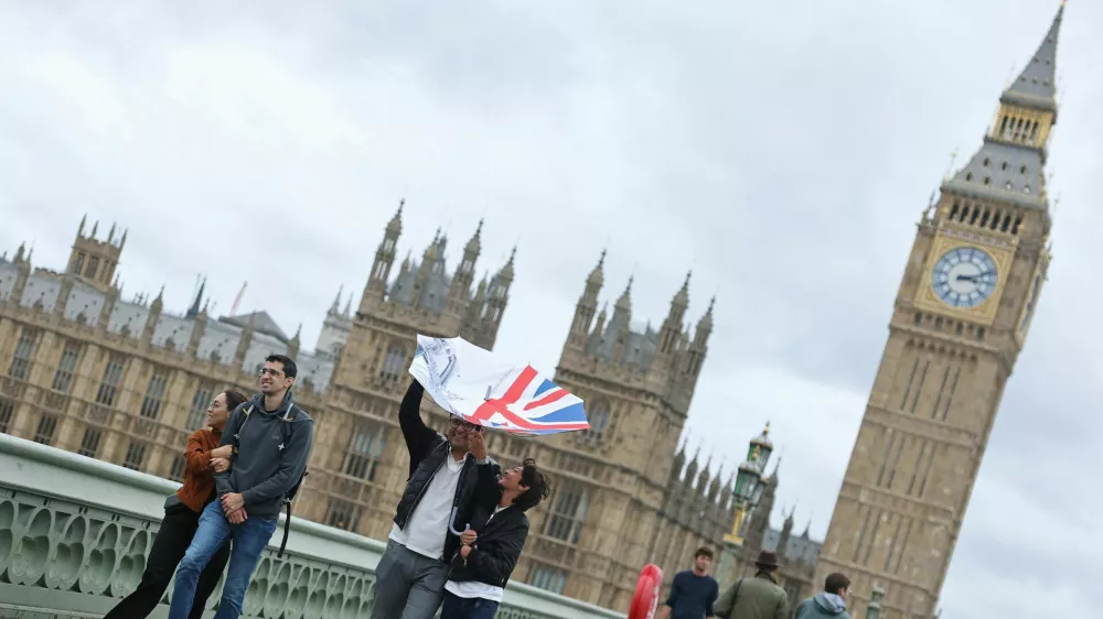 A person struggles to use their umbrella in the wind, as Storm Floris hits parts of Britain, near the Houses of Parliament in London, Britain, August 4, 2025. REUTERS/Toby Melville