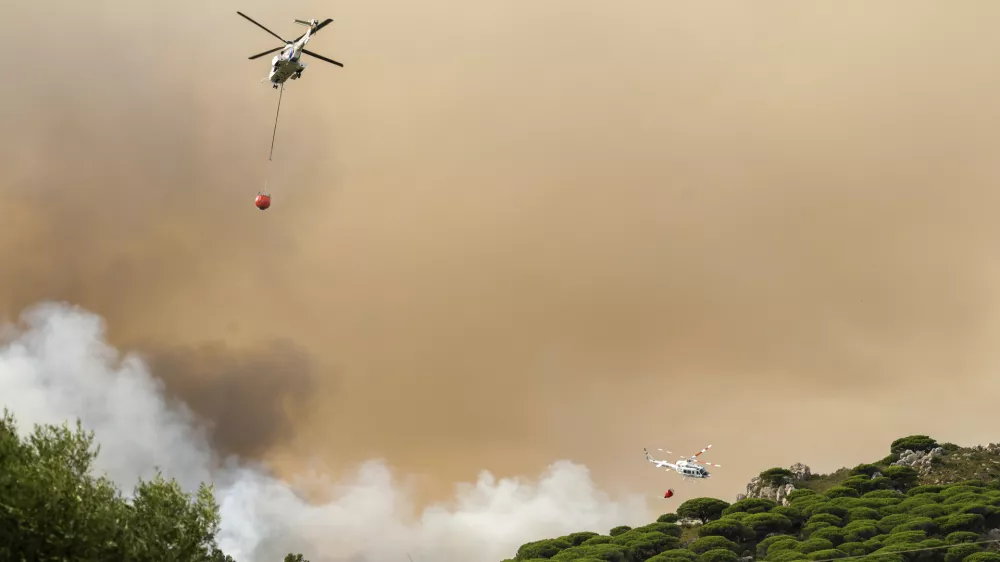 Firefighting helicopters drop water to extinguish a blaze in Torre de la Pe&ntilde;a, southern Spain, Tuesday, Aug. 5, 2025. (Nono Rico/Europa Press via AP)