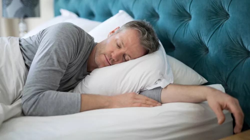 Man sleeping on bed in bedroom at home