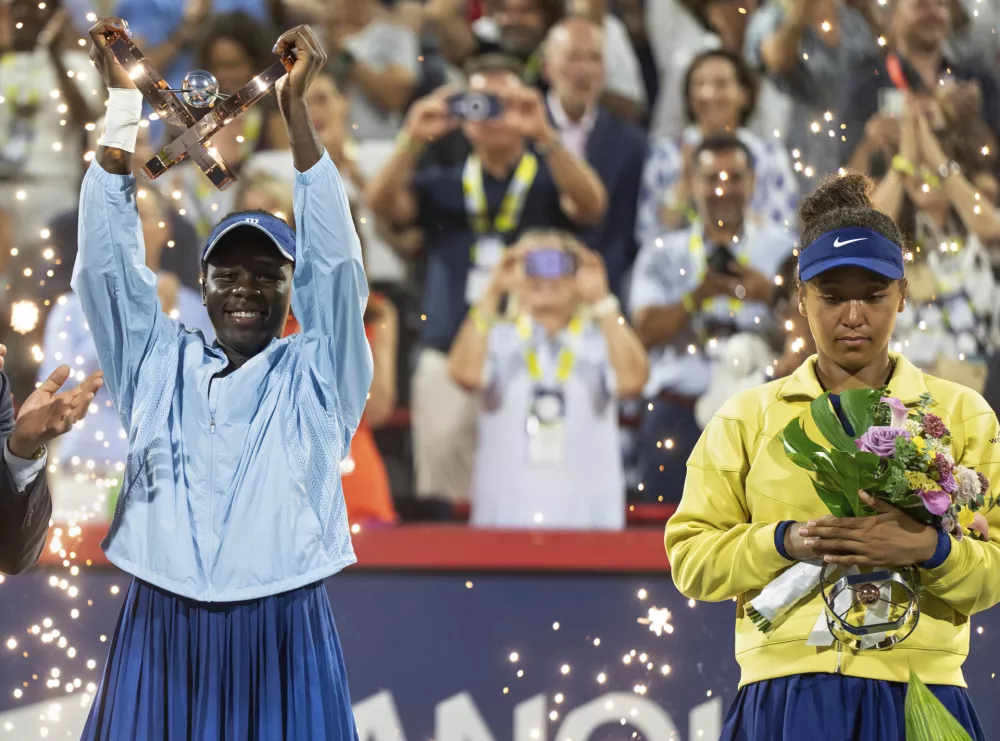 Victoria Mboko of Canada, left, lifts the trophy following her win over Naomi Osaka of Japan after final tennis action at the National Bank Open in Montreal, Thursday, Aug. 7, 2025. (Christinne Muschi/The Canadian Press via AP)