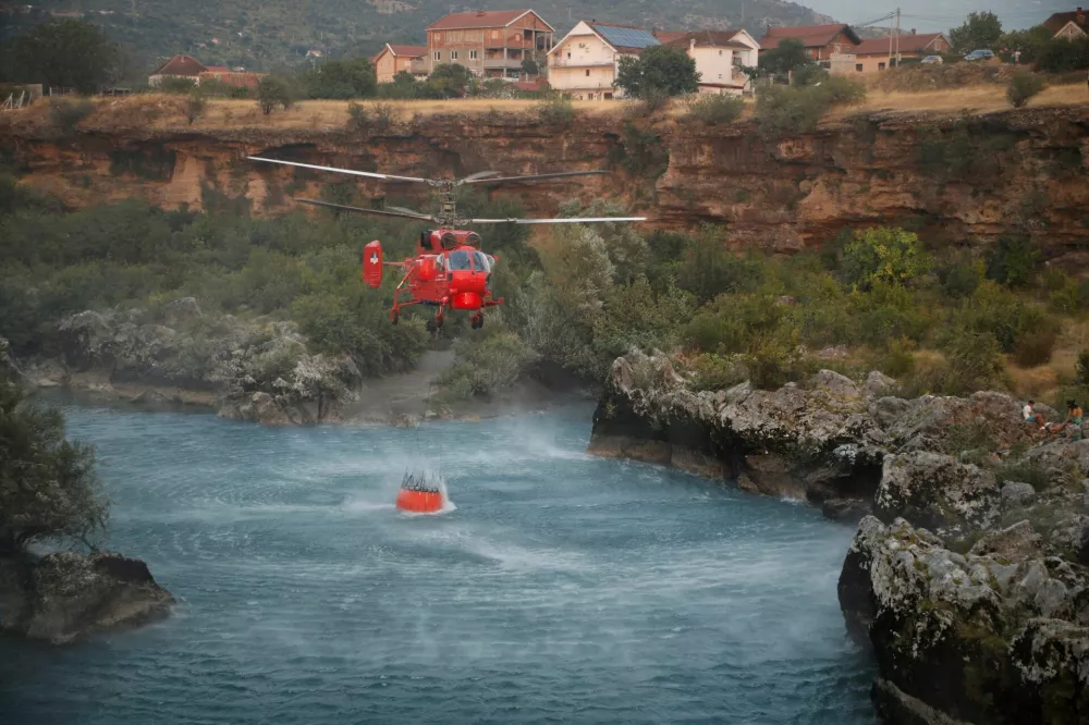 A firefighting helicopter collects water from river Moraca, in Stara Zlatica suburbs, as temperature rises during a heatwave in Podgorica, Montenegro, August 11, 2025. REUTERS/Stevo Vasiljevic