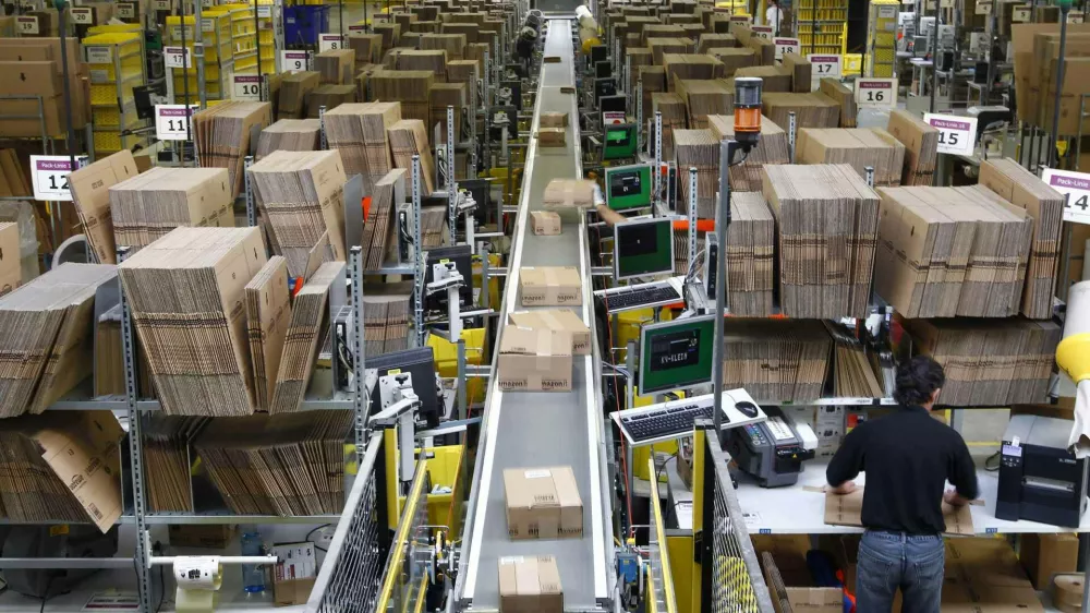 Workers pack boxes at Amazon's logistics centre in Graben near Augsburg December 16, 2013. Workers at Amazon.com's German operations were set to go on strike on Monday, in the middle of the crucial Christmas holiday season, in a dispute over pay that has been raging for months. The Verdi union said workers would strike in Amazon's logistic centres in Bad Hersfeld and Leipzig and, for the first time, in Graben. REUTERS/Michaela Rehle (GERMANY - Tags: BUSINESS EMPLOYMENT)