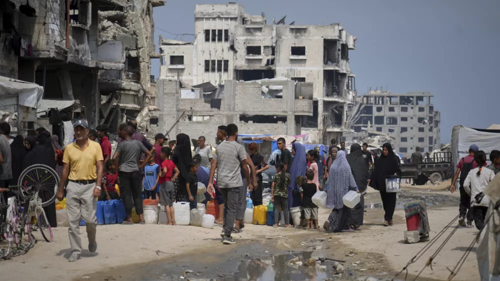 In the summer heat, Palestinians line up to collect water from a distribution point in Gaza City, Tuesday, Aug. 12, 2025. (AP Photo/Jehad Alshrafi)