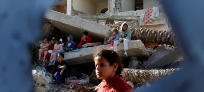 Palestinian children sit on rubble as they wait to receive food cooked by a charity kitchen, during the Muslim holy month of Ramadan, in Rafah, in the southern Gaza Strip, March 13, 2025. REUTERS/Hatem Khaled