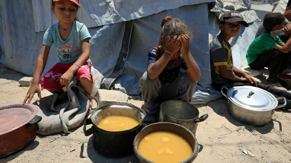Palestinian children react near pots of food from a charity kitchen, amid a hunger crisis, in Gaza City, July 25, 2025. REUTERS/Dawoud Abu Alkas