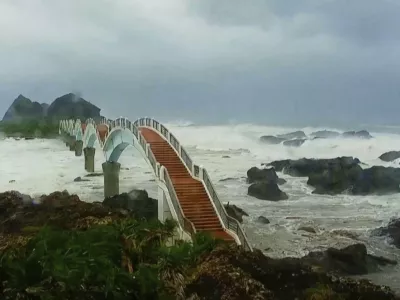 In this image made from video released by Taitung County Government, strong waves and heavy rain pound the Sansiiantai tourist spot on Aug. 13, 2025, as Typhoon Podul reaches Taitung, eastern Taiwan. (Taitung County Government via AP)