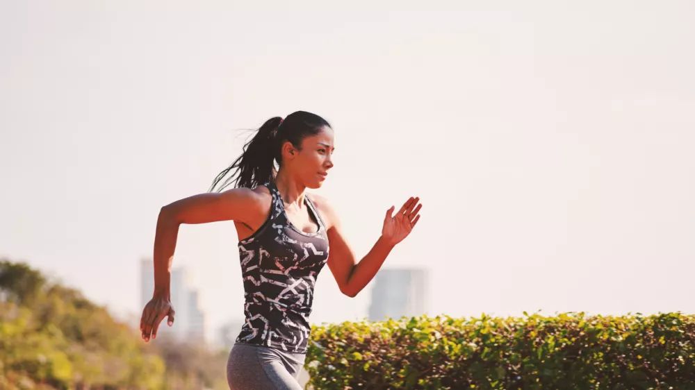 Sport girl in sporty outfit running at the lane in the park