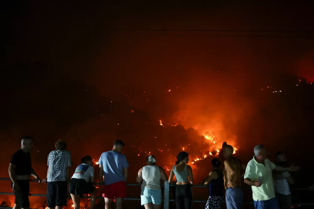 Locals, who left their homes watch, as wildfire continues to burn, in Delvina, Albania, August 12, 2025. REUTERS/Florion Goga