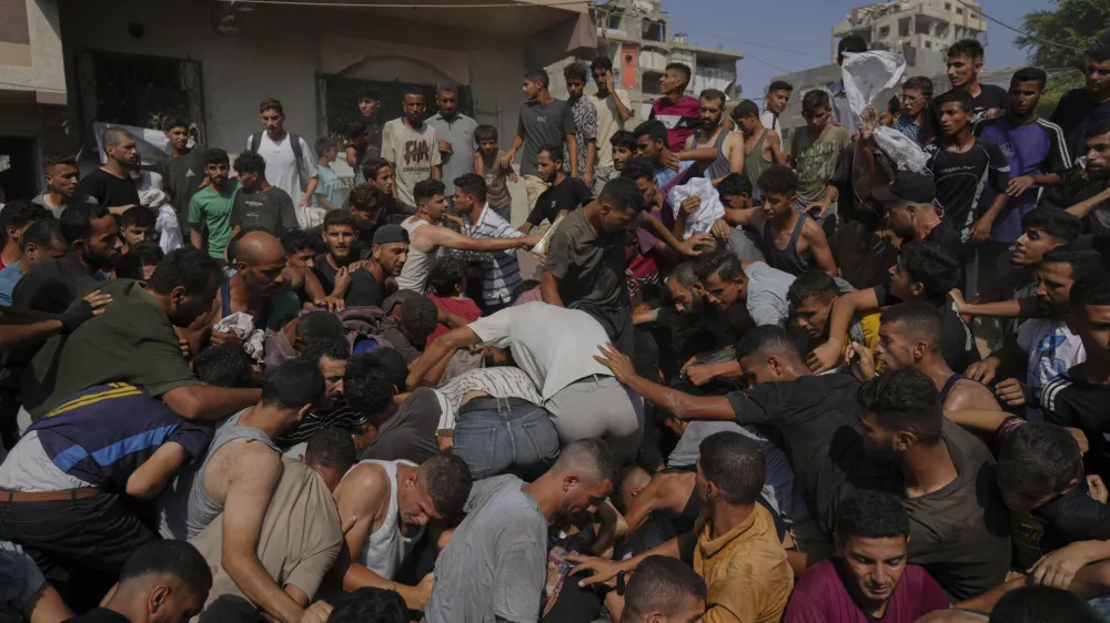 Palestinians struggle to collect humanitarian aid airdropped by parachutes into Gaza City, northern Gaza Strip, Thursday, Aug. 14, 2025. (AP Photo/Jehad Alshrafi)