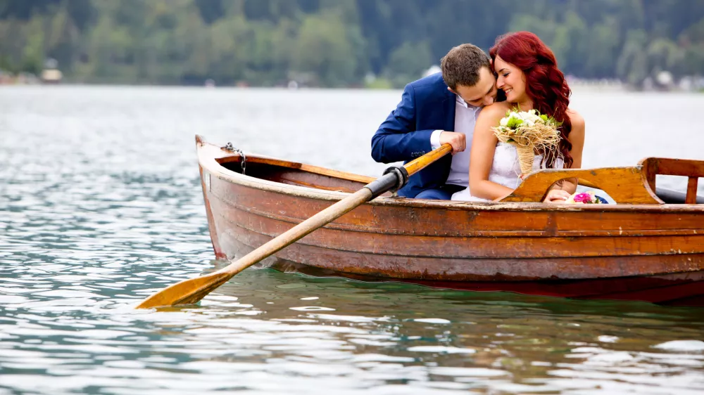 Young attractive wedding couple sharing love in a boat on beautiful lake / Foto: Jeliva