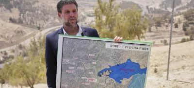 CORRECTS DAY Israeli Finance Minister Bezalel Smotrich holds a map that shows the E1 settlement project during a press conference near the settlement of Maale Adumim, in the Israeli-occupied West Bank, Thursday, Aug. 14, 2025. (AP Photo/Ohad Zwigenberg)