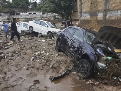 Local residents look damaged cars trapped in a mud following flash flooding due to heavy rains at a neighbourhood of Mingora, the main town of Swat Valley, northwestern Pakistan, Friday, Aug. 15, 2025. (AP Photo/Naveed Ali)
