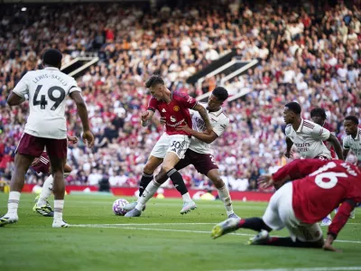 Arsenal's William Saliba, ceter right, challenges Manchester United's Benjamin Sesko during the English Premier League soccer match between Manchester United and Arsenal at Old Trafford stadium in Manchester, England, Sunday, Aug. 17, 2025. (AP Photo/Dave Thompson)