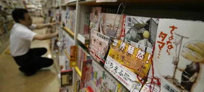 A Japanese Manga "Ichi Efu" (2nd R), which centres on workers at the Fukushima Daiichi nuclear plant, is seen on a bookshelf as a staff adjusts manga comics at a bookstore in Tokyo June 23, 2014. Japanese farmers in Fukushima try to convince sceptical visitors that their crops are safe from radiation. Blood trickles from the nose of a reporter who visits the area. These are just two of the tales from the aftermath of the world's worst nuclear disaster in 25 years - as told by manga, Japan's ubiquitous comics for adults and teens, which have taken up Fukushima on an unprecedented scale even as Japanese film largely avoids the topic. Picture taken June 23, 2014. REUTERS/Yuya Shino (JAPAN - Tags: SOCIETY DISASTER) / Foto: Yuya Shino