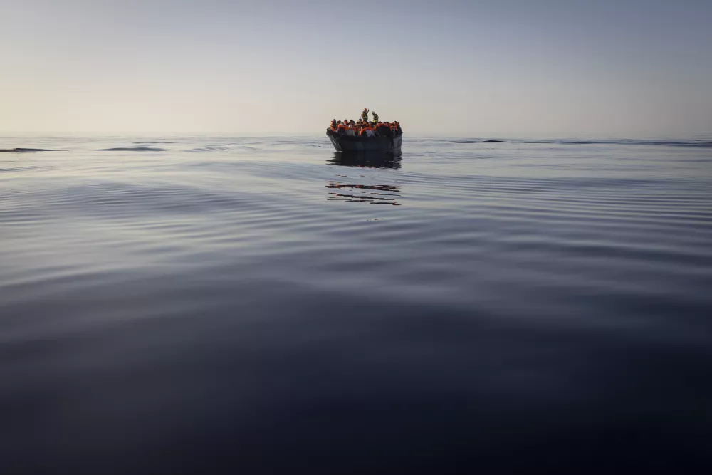 FILE - Migrants with life jackets provided by volunteers of the Ocean Viking, a migrant search and rescue ship run by NGOs SOS Mediterranee and the International Federation of Red Cross (IFCR), still sail in a wooden boat as they are being rescued, on Aug. 27,&nbsp;2022. The border and coast guard agency Frontex estimated that more than 50,300 attempts were made to enter the EU without authorization from January to May. It's more than double the number in the same period last year, and the most since 2017. (AP Photo/Jeremias Gonzalez, File)