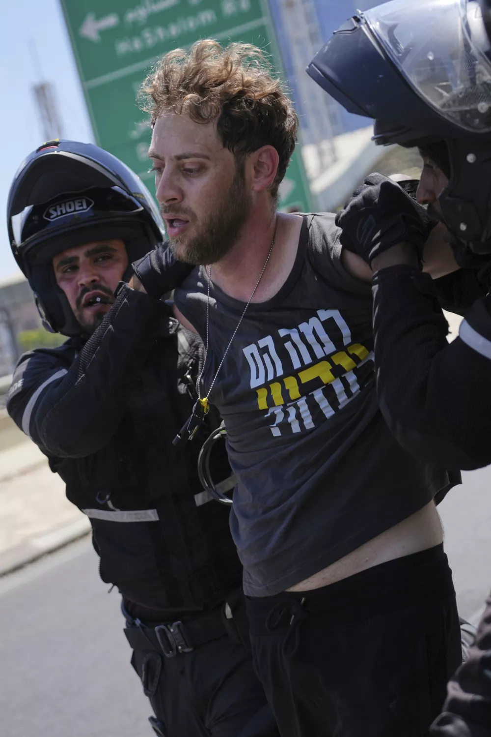 A demonstrator is detained for blocking a road with others during a protest demanding the immediate release of hostages held by Hamas and calling for the Israeli government to reverse its decision to take over Gaza City and other areas in the Gaza Strip, in Tel Aviv, Israel, Aug. 17, 2025. (AP Photo/Ohad Zwigenberg)