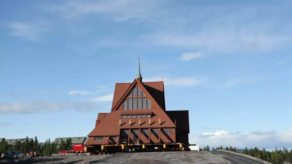 Workers stand in front of Kiruna's old wooden church on its final destination after a two-day relocation trip to a new site next to a cemetery, to save its wooden walls from ground subsidence and the expansion of the world's largest underground iron ore mine, in Kiruna, Sweden August 20, 2025. REUTERS/Leonhard Foeger