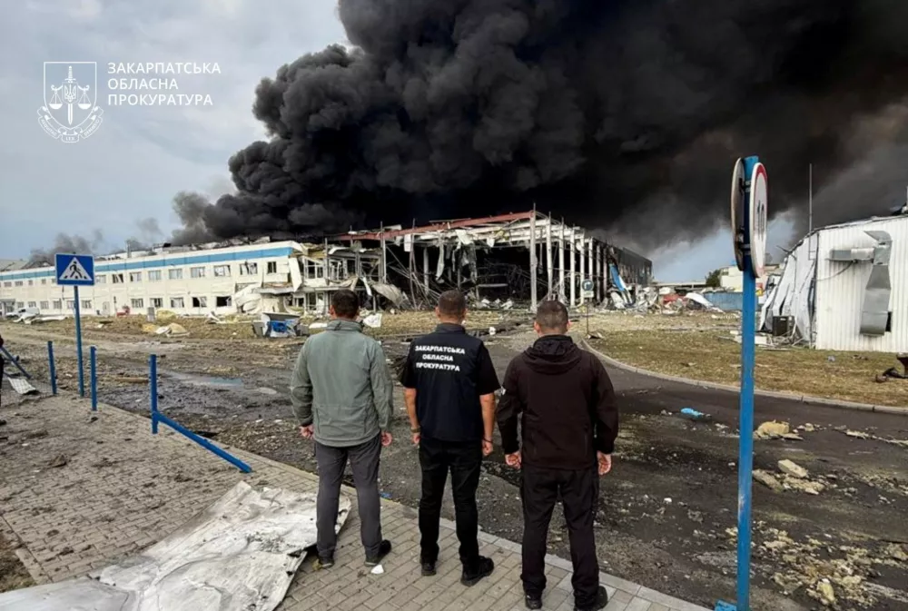 Law enforcement personnel watch as smoke rises over the Flextronics factory hit by a Russian missile strike, amid Russia's attack on Ukraine, in Mukachevo, Zakarpattia region, Ukraine August 21, 2025. Zakarpattia Regional Prosecutor's Office/Handout via REUTERS ATTENTION EDITORS - THIS IMAGE HAS BEEN SUPPLIED BY A THIRD PARTY. DO NOT OBSCURE LOGO. NO RESALES. NO ARCHIVES.   TPX IMAGES OF THE DAY
