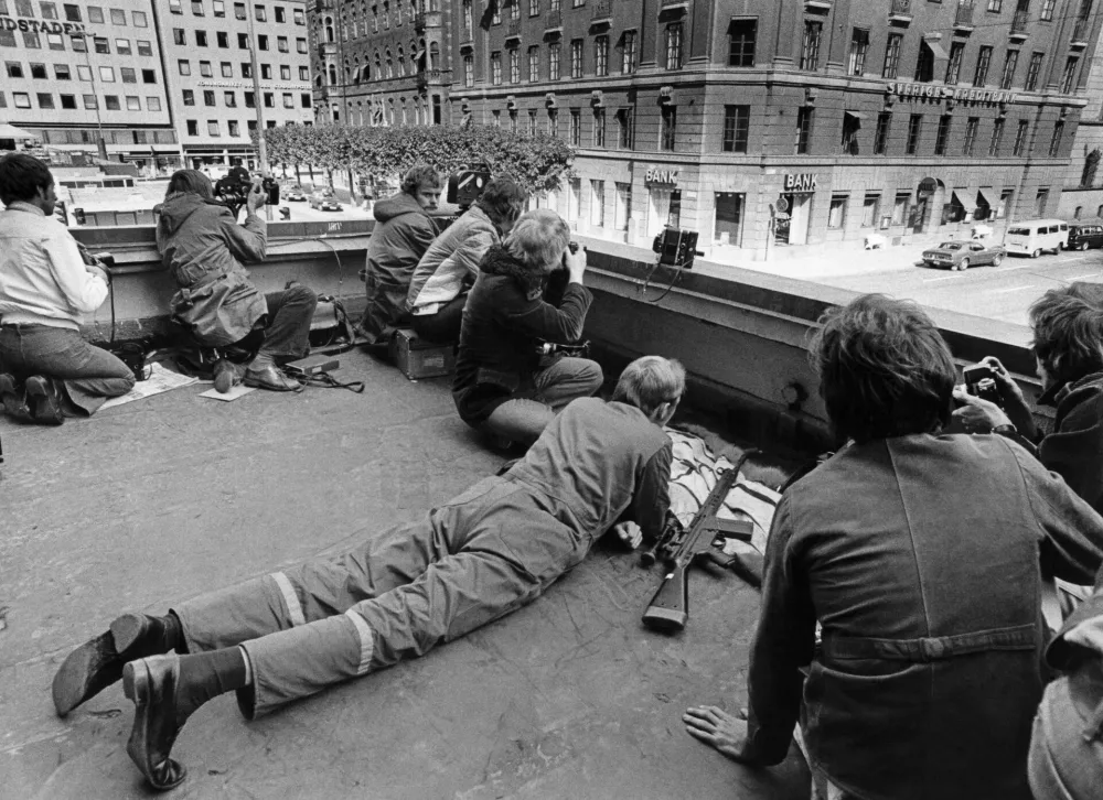 Policija in novinarji na strehi, s katere so imeli lep pregled na dogajanje okoli banke. / Foto: Profimedia