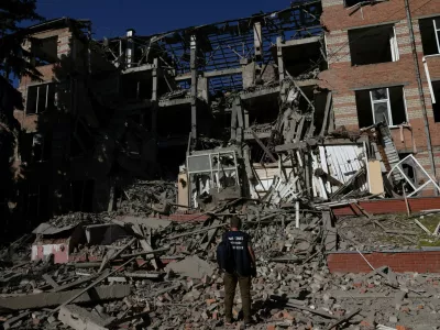 A worker from the war crimes prosecutor's office takes in the damage from overnight shelling that landed on a building of Kharkiv's Housing and Communal College as Russia's attack on Ukraine continues in Kharkiv, Ukraine, June 21, 2022. REUTERS/Leah Millis