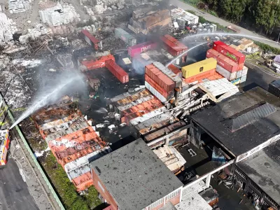 26 August 2025, Hamburg: Aerial view of firefighters extinguishing a fire in an industrial area in the port of Hamburg, where a major fire had broken out the day before. Photo: Marcus Golejewski/dpa
