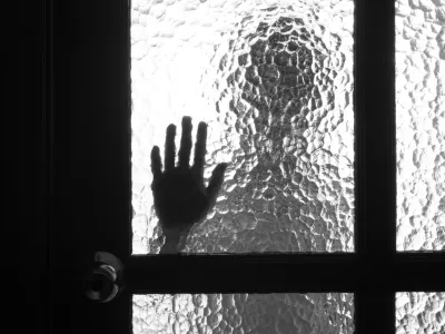 Photo of person standing over the door and its hand on the glass near the handle / Foto: Vitalii Petrushenko