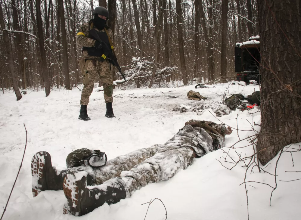 A volunteer of the Ukrainian Territorial Defense Forces looks at a dead body of a soldier lying in a forest in the outskirts of Kharkiv, Ukraine's second-largest city, Monday, March 7, 2022. Russia announced yet another cease-fire and a handful of humanitarian corridors to allow civilians to flee Ukraine. Previous such measures have fallen apart and Moscow&acirc;&euro;&trade;s armed forces continued to pummel some Ukrainian cities with rockets Monday. (AP Photo/Andrew Marienko).