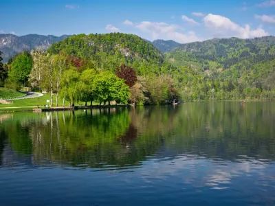 Calm water reflecting surrounding trees and mountains in Lake Bled, Slovenia