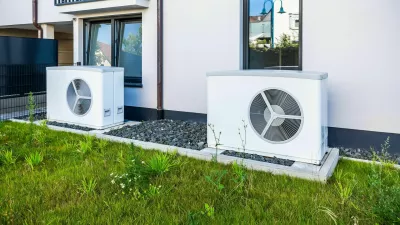 2XWNAMH Two air source heat pumps installed outside of new and modern city house, green renewable energy concept of heat pump