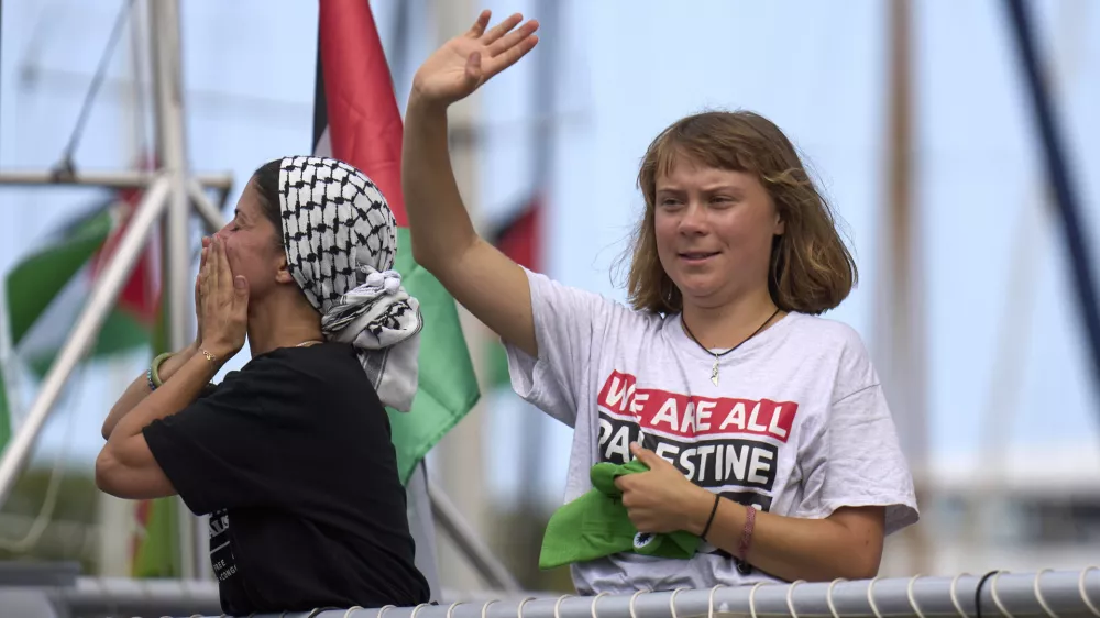 Swedish climate activist Greta Thunberg waves from a boat taking part in a civilian flotilla bound for Gaza, aiming to break the Israeli blockade and deliver humanitarian aid, in Barcelona, Spain, Sunday, Aug. 31, 2025. (AP Photo/Emilio Morenatti)