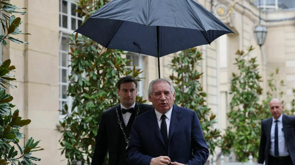 French Prime Minister Francois Bayrou walks under an umbrella as he arrives for a series of consultations with political parties, a week before a confidence vote he is seeking from the National Assembly on the budget issue, at the Hotel Matignon in Paris, France, September 2, 2025. REUTERS/Gonzalo Fuentes