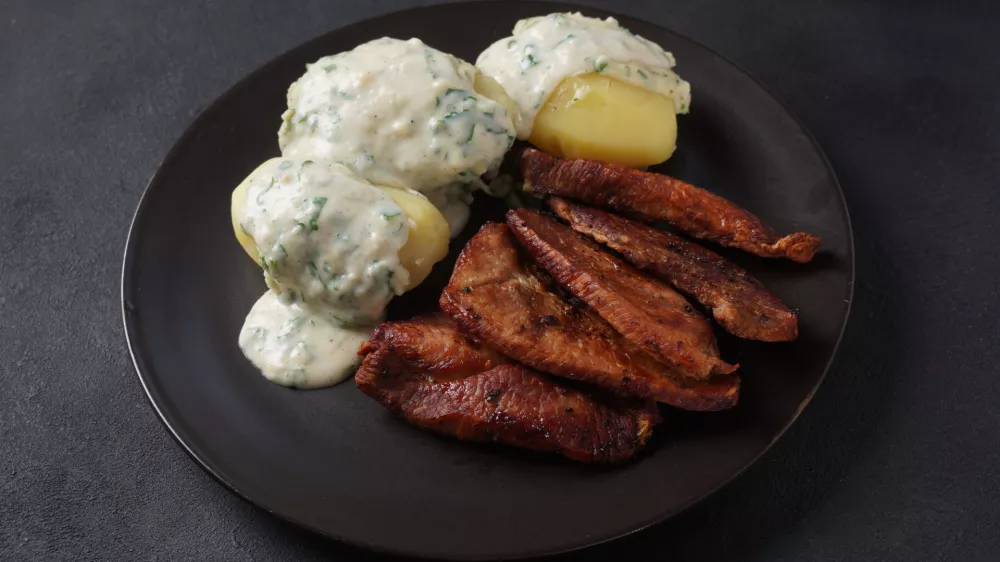 Crispy fried pork with creamy parsley sauce and boiled potato in the plate on the table or stegt fl&aelig;sk, a classic Danish cuisine. / Foto: Nataly Hanin