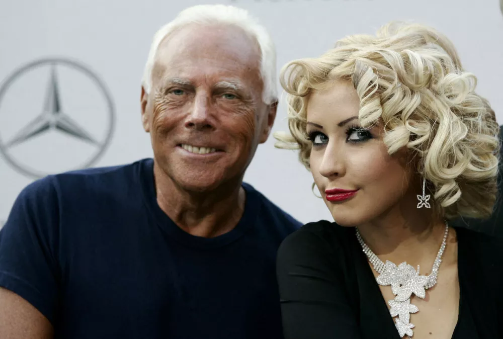 FILE PHOTO: Italian designer Giorgio Armani (L) and pop star Christina Aguilera take part in a press conference for a new Mercedes-Benz car in Milan September 9, 2004. REUTERS/Daniele La Monaca/File Photo