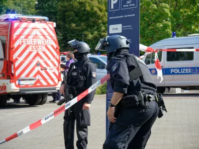 05 September 2025, North Rhine-Westphalia, Essen: Police officers stand at a barrier with flutter tape at a vocational college in Essen. A teacher at the vocational college was attacked and injured by a perpetrator with a knife. According to security sources, the perpetrator was a pupil at the school. He fled the scene. Photo: Henning Kaiser/dpa