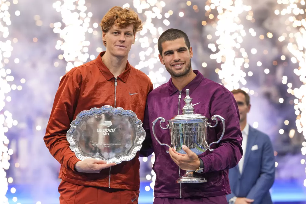 Carlos Alcaraz, of Spain, poses for photos with Jannik Sinner, of Italy, after winning the men's singles final of the U.S. Open tennis championships, Sunday, Sept. 7, 2025, in New York. (AP Photo/Kirsty Wigglesworth)