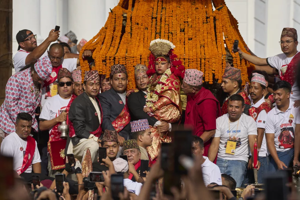 Kumari, Nepal's living goddess, is carried high beside the chariot which she will ride, pulled by devotees, around the center of the capital in Kathmandu, Nepal, Saturday, Sept. 6, 2025. (AP Photo/Niranjan Shrestha)