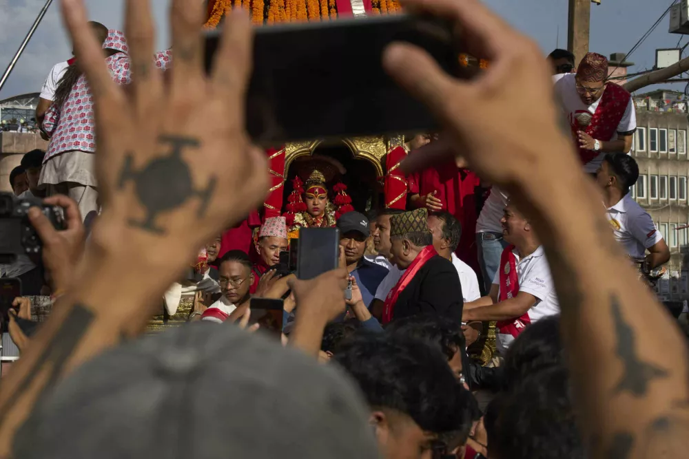 A devotee takes photos of living goddess Kumari during Indra Jatra, a festival that marks the end of the rainy season in Kathmandu, Nepal, Saturday, Sept. 6, 2025. (AP Photo/Niranjan Shrestha)