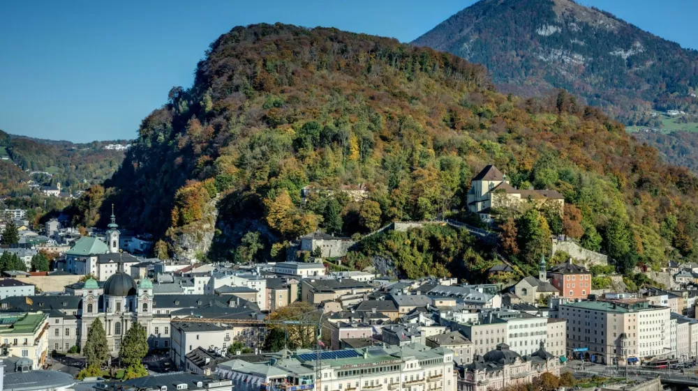 Dvorec Paschinger Schlossl, ki ga je obnovil Porsche, je skrit v zelenju hriba Kapuzinerberg, levo od bolje videnega gradu na desnem delu fotografije. Foto: Profimedia 