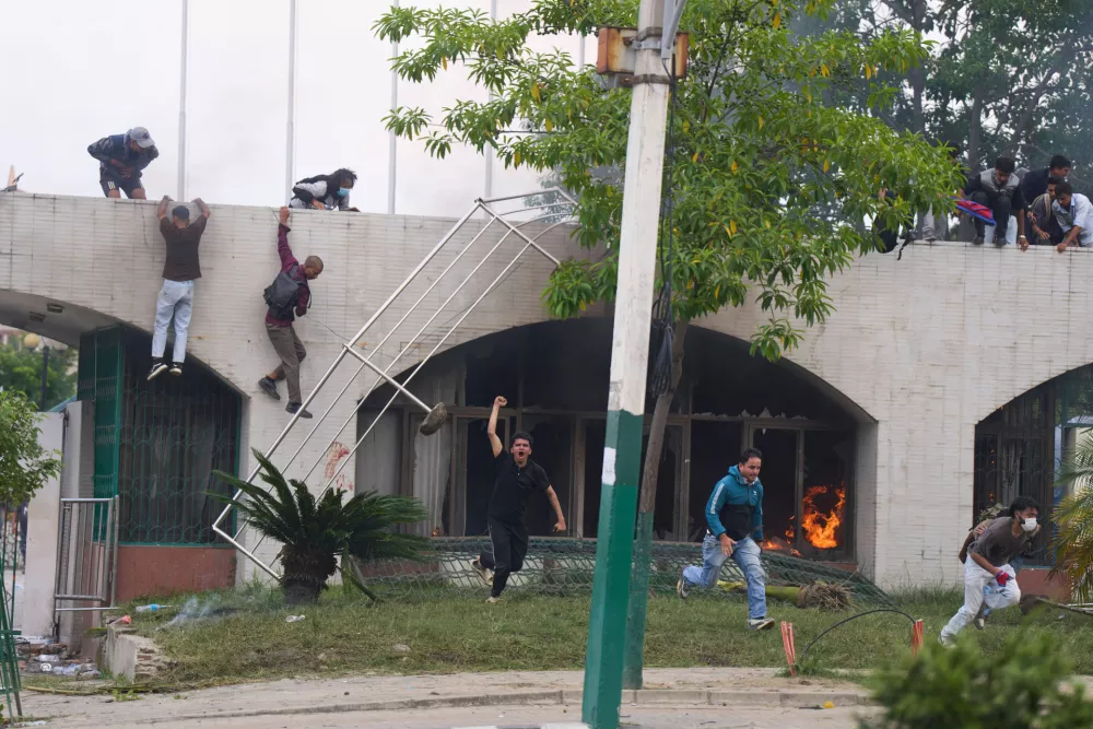 Protesters jump from a burning building during clashes with riot police in Kathmandu, Nepal, Monday, Sept. 8, 2025. (AP Photo/Niranjan Shrestha)