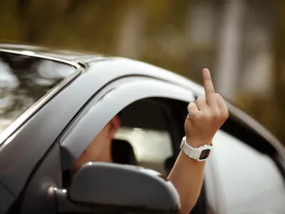 young driver shows middle finger, natural light, selective focus