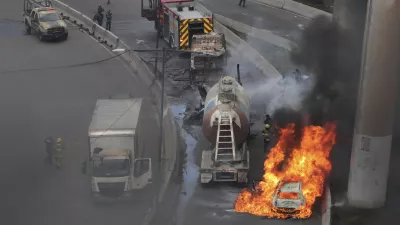 A vehicle burns near the site of a gas tanker explosion under a highway overpass in Mexico City, Wednesday, Sept. 10, 2025. (AP Photo/Tristan Velazquez)