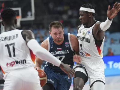 Germany's Dennis Schroder, left, Slovenia's Luka Doncic, centre, Germany's Isaac Bonga during the Eurobasket, European Basketball Championship quarter final match between Germany and Slovenia at the Riga Arena in Riga, Latvia, Wednesday, Sept. 10, 2025. (AP Photo/Sergei Grits)