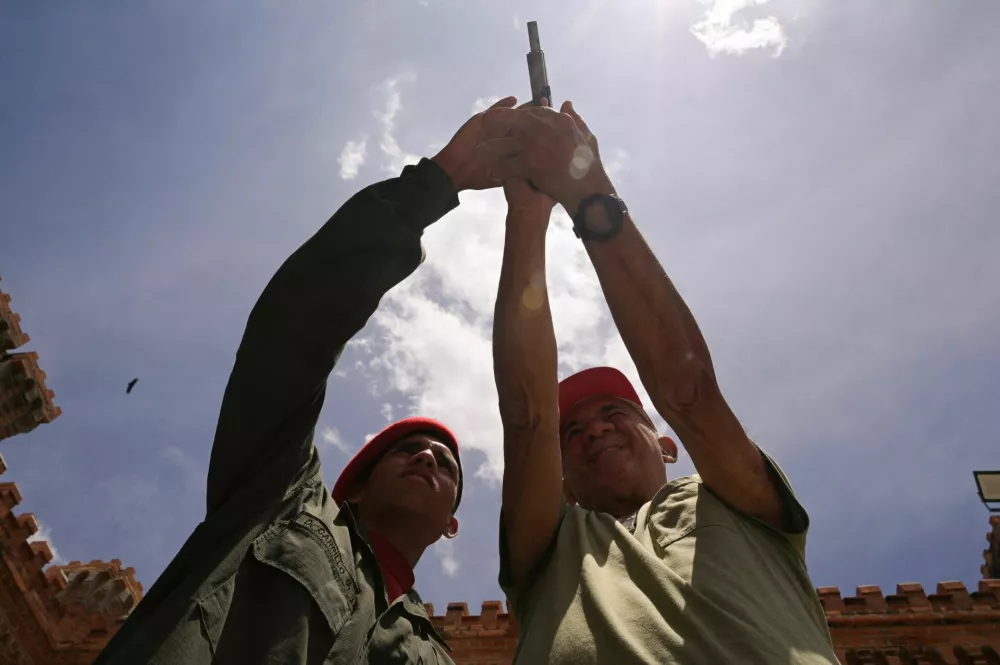 A member of the Presidential Guard shows a man who signed up to join the National Bolivarian Militia how to use weapon during a training exercise at the 4F military fort, following Venezuelan President Nicolas Maduro's call for a nationwide military training, amid heightened tensions with the U.S., in Caracas, Venezuela September 13, 2025. REUTERS/Gaby Oraa