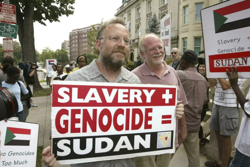 FILE - Founders of Ben & Jerry's Ice Cream Jerry Greenfield, left, and Ben Cohen, pink shirt, protest in front of Sudan's embassy July 29, 2004, in Washington. (AP Photo/Charles Dharapak, File)